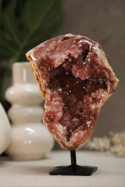 Geode crystal on a stand with decorative vases in the background